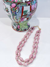 Load image into Gallery viewer, A pink Chinoiserie double strand necklace made of ginger jar shaped porcelain beads is laying flat beside a Rose Medallion vase.